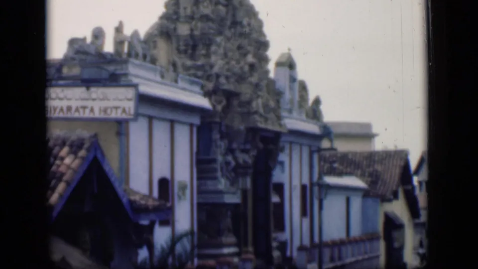 1946 Bombay 8mm frame showing an ornate temple tower above low buildings and a partially visible hotel sign.