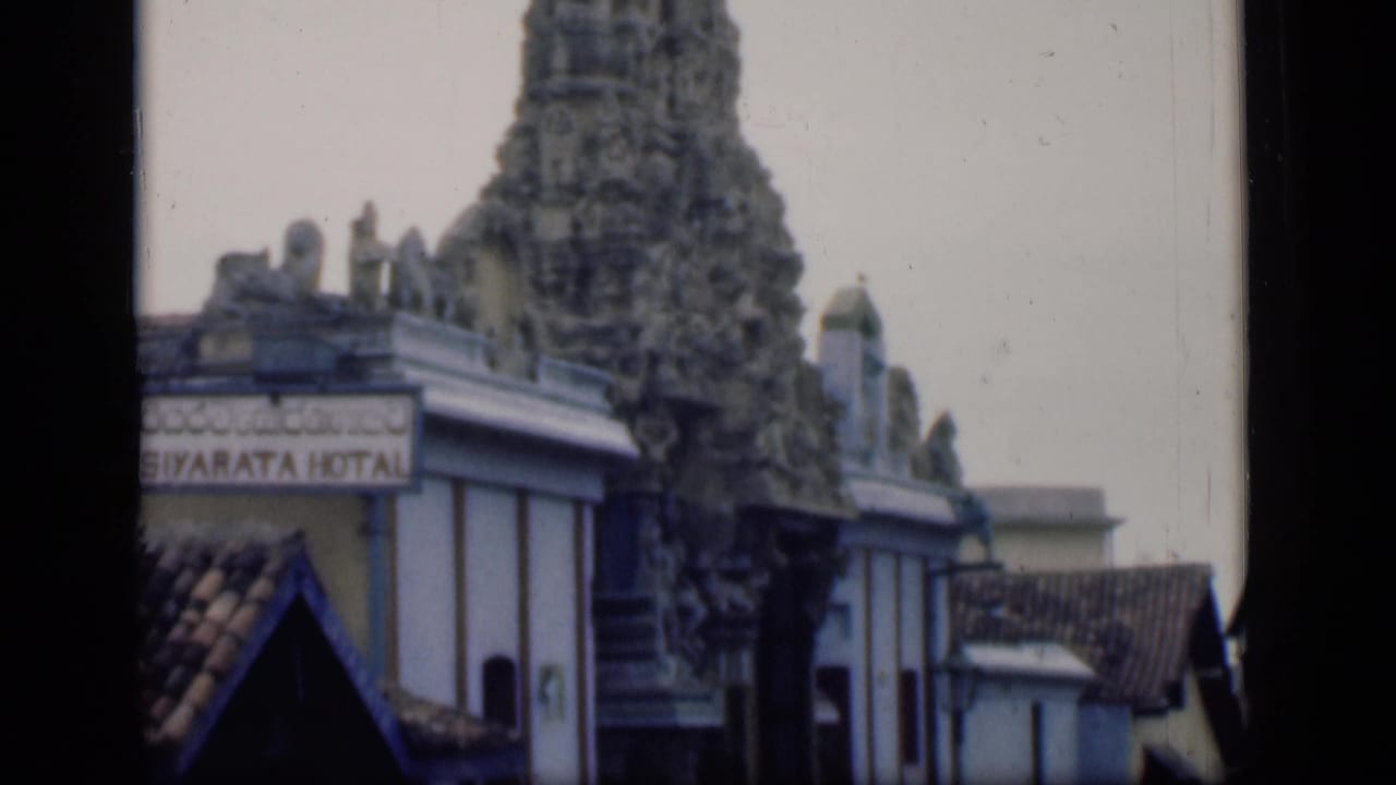 Temple tower and roofline seen beside a partially readable hotel sign.