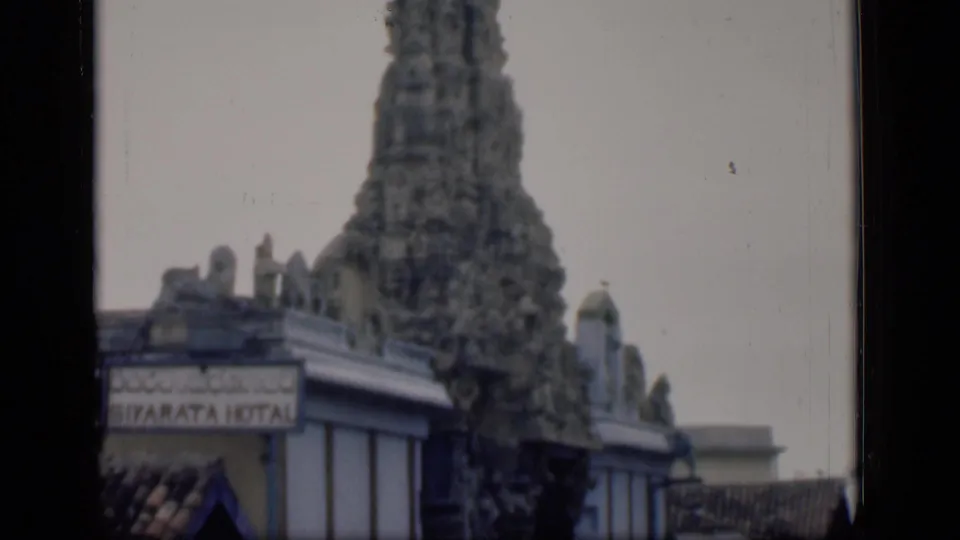 1946 Bombay frame with the tall carved temple tower rising above a building corner and tiled roof.