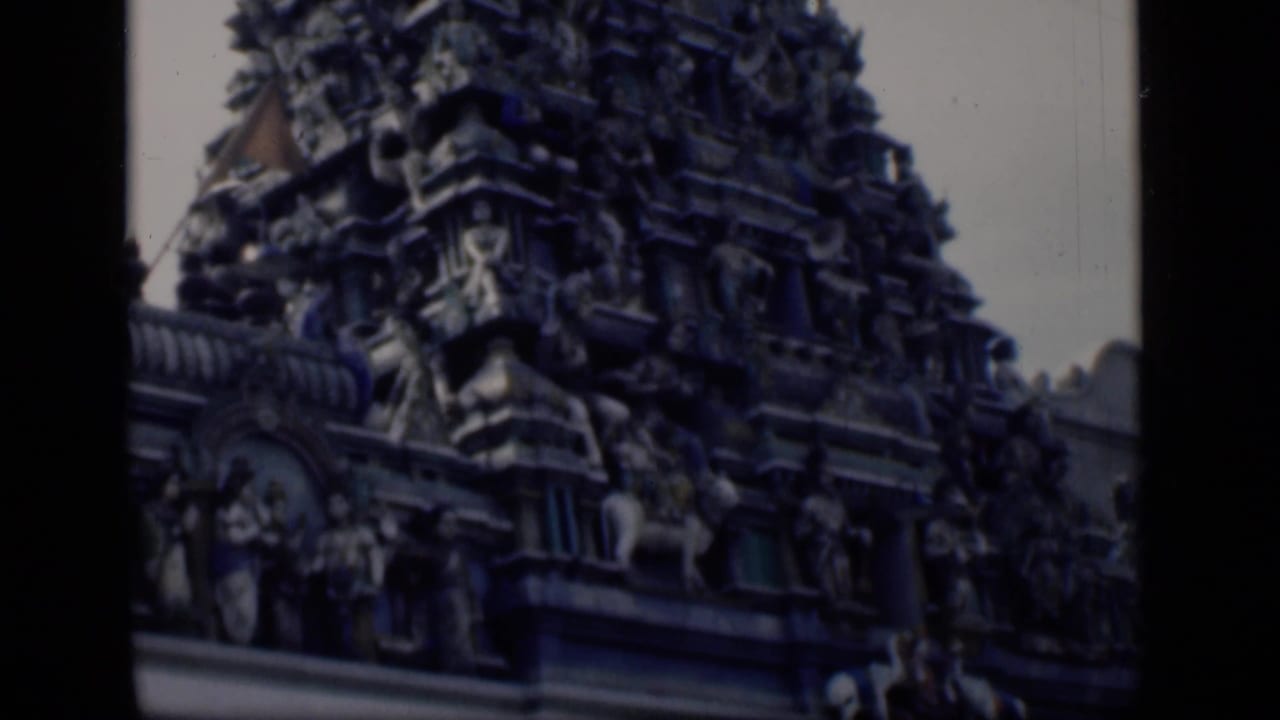 Closer view of a carved temple tower with stacked sculptural figures and roofline detail.