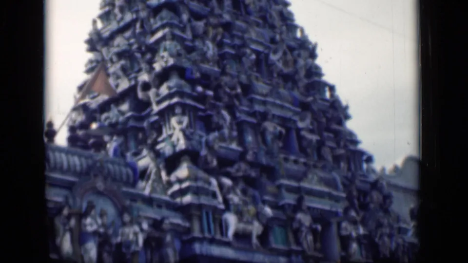 1946 Bombay 8mm frame focused on the temple gopuram, with sculptural figures, tiered ornament, and visible film borders.