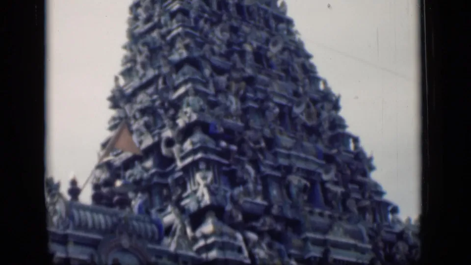 Close 1946 Bombay frame of the ornate gopuram, showing carved figures and architectural layers above the temple roofline.