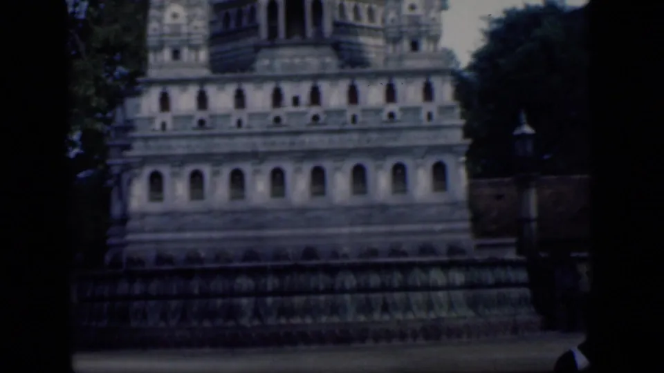 1946 Bombay home-movie view of the temple base below the gopuram, with arched openings, trees, and a boundary wall.