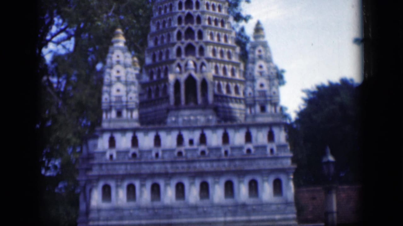 1946 Bombay frame with a temple-like landmark, repeated arched niches, tree cover and a low boundary wall.