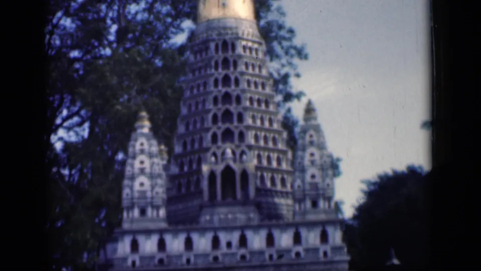 1946 Bombay 8mm frame showing the golden-topped central spire of an ornate temple-like structure among trees.