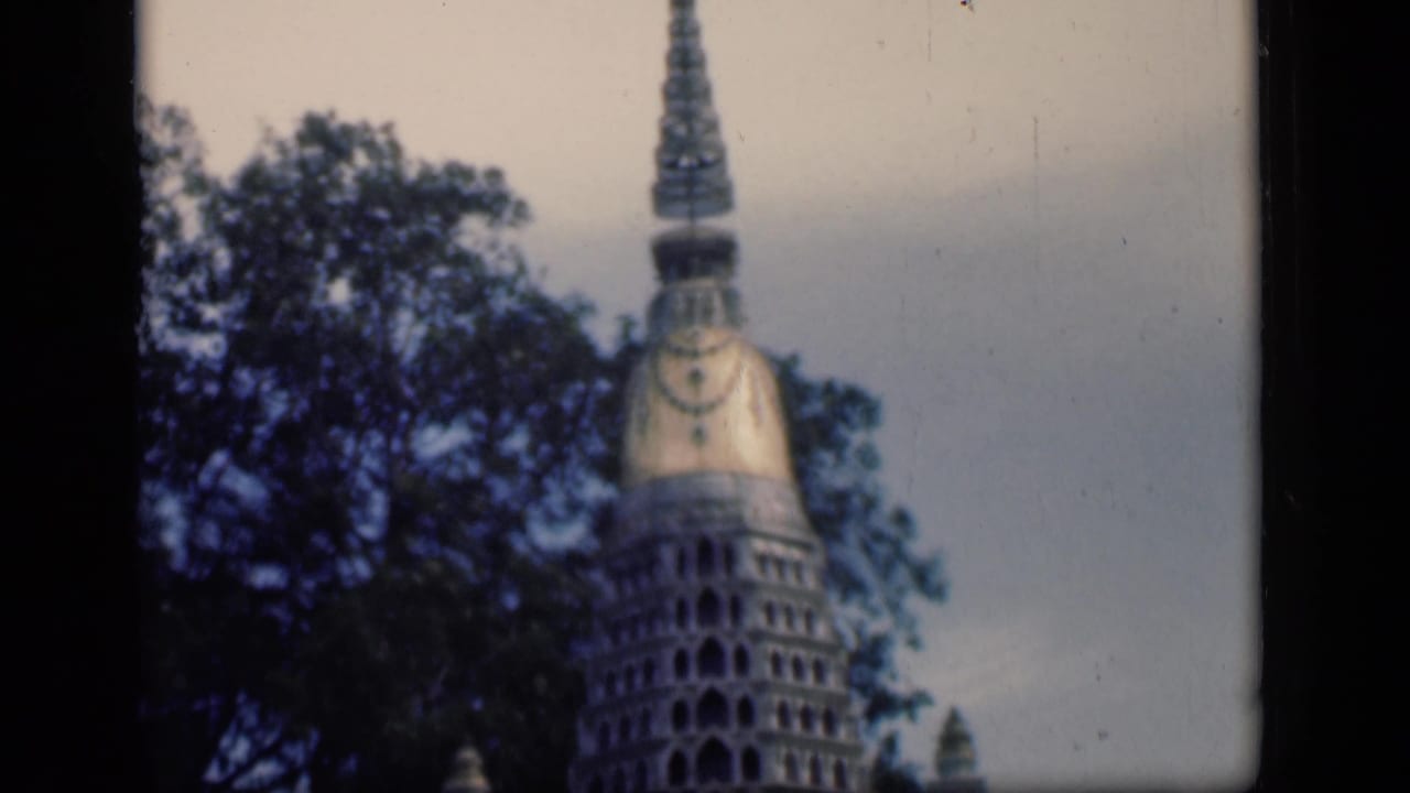 1946 Bombay home-movie frame showing a tower-like architectural structure partly obscured by trees.