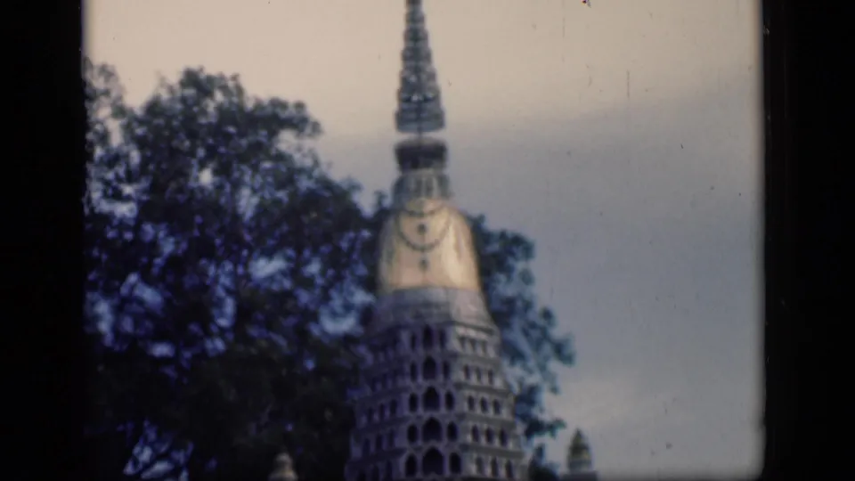 1946 Bombay home-movie frame showing a tower-like architectural structure partly obscured by trees.
