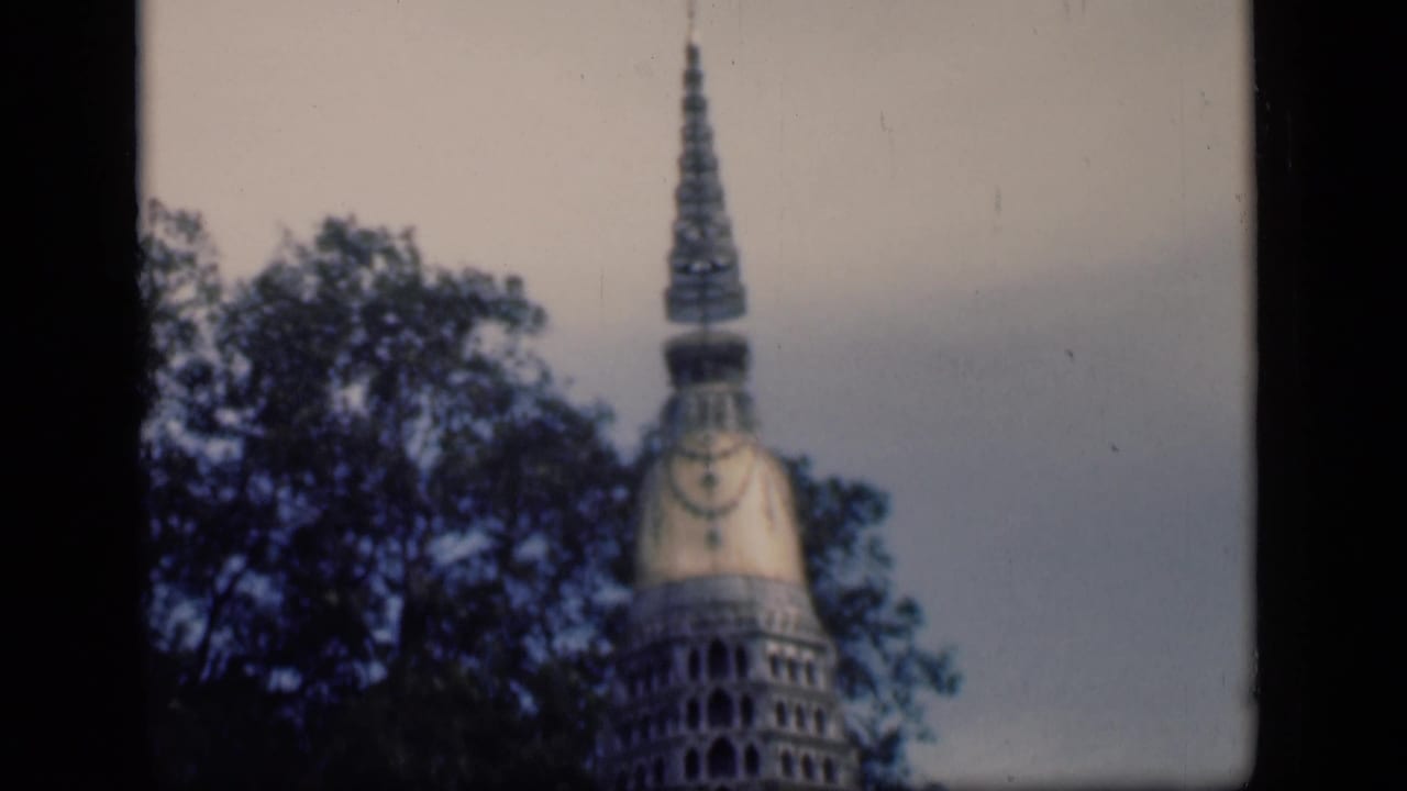 1946 Bombay travel-film view of a tower-like structure behind trees, framed by dark 8mm borders.