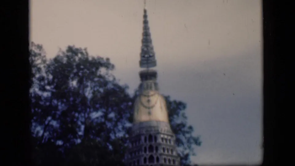 1946 Bombay travel-film view of a tower-like structure behind trees, framed by dark 8mm borders.