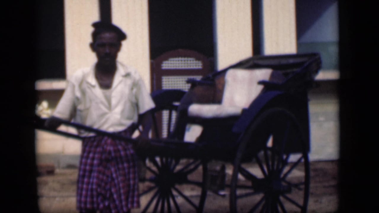 In Bombay, India, a rickshaw driver stands holding the poles of a hand-pulled rickshaw in 1946 home-movie footage.