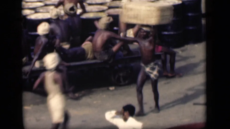 Several dock workers are seen around a cart and stacked cargo in likely Bombay, India, in 1946 footage.