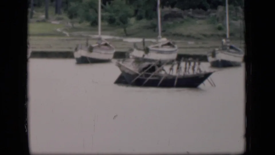 1946 Bombay home-movie frame of small craft along calm water, including a boat with visible oars.