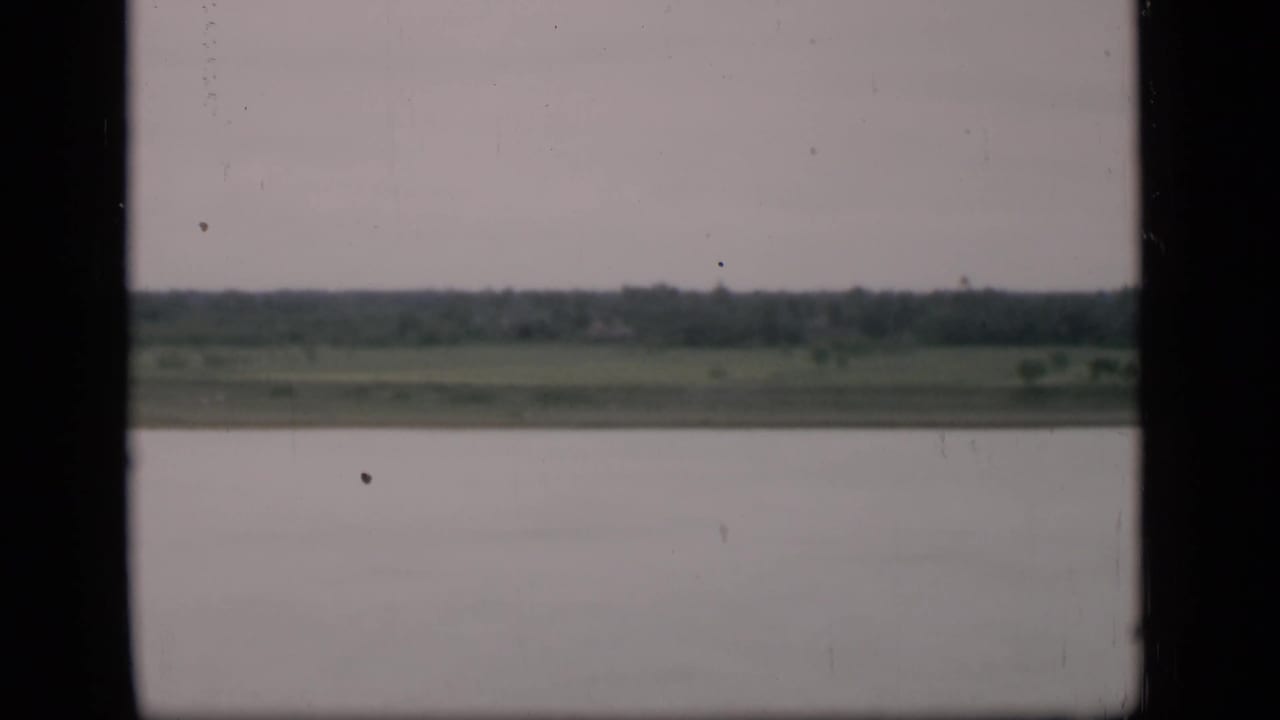 Wide water and distant shoreline seen through dark vertical frame edges, with no vessel in view.
