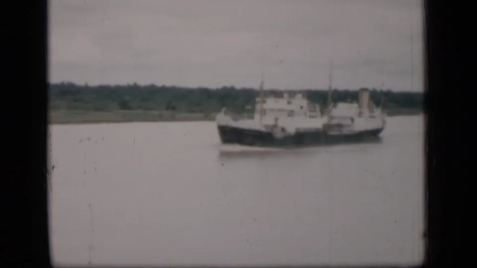 A mid-distance view of the cargo ship on Bombay waters, framed by 8mm gate edges and muted archival color.