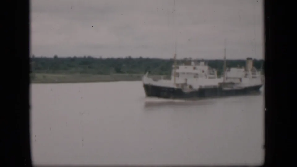 1946 Bombay 8mm frame showing a large cargo ship moving across a broad river under muted overcast light.