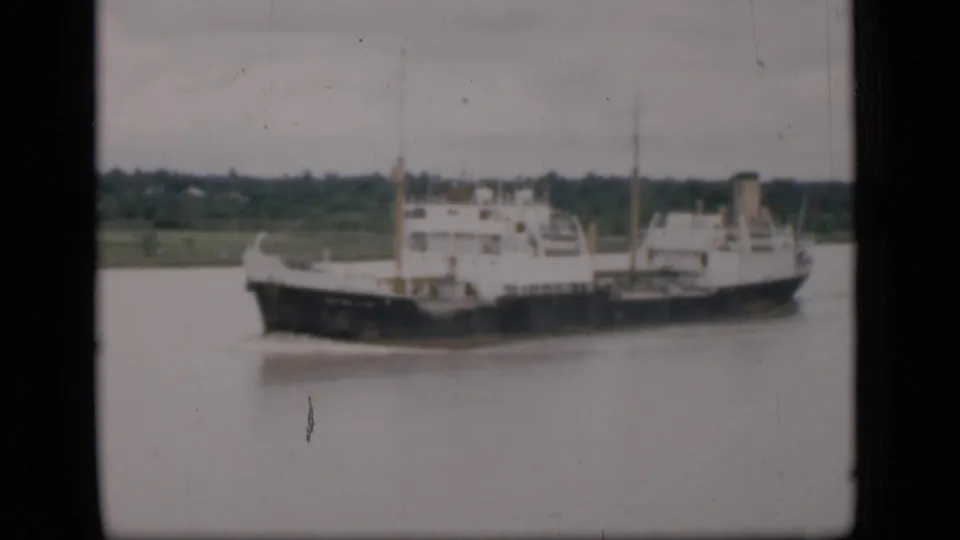 1946 Bombay archival home-movie frame of a large river cargo ship with soft focus, scratches, and overcast sky.