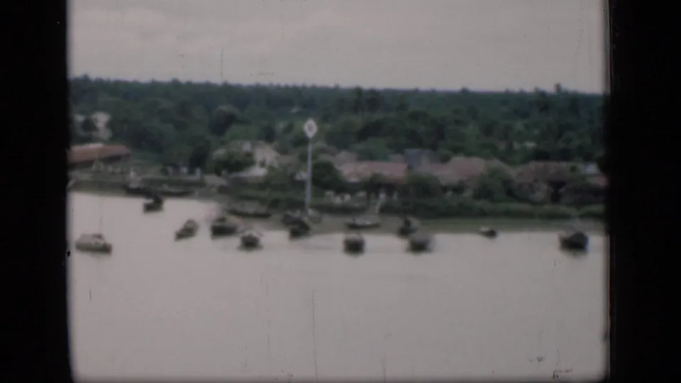 The clip shifts to a wider 1946 Bombay river view with small boats on the water and low buildings among trees across the bank.