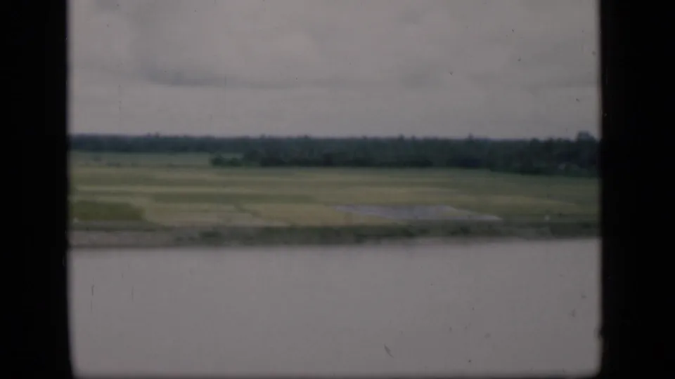 Bombay, India 1946 footage appears to show a broad waterside view of green fields and a distant wooded bank from a moving boat.