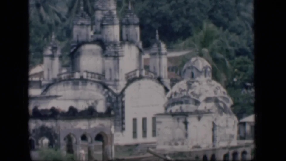 1946 Bombay 8mm view of the domed complex, with tall spires, arched lower walls, palm trees, and dense greenery.