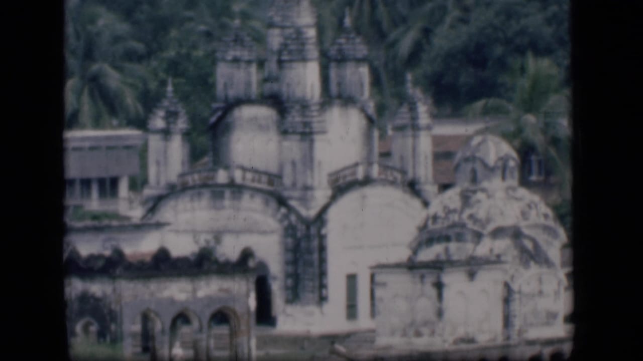 Weathered white domed temple with palm trees behind it.