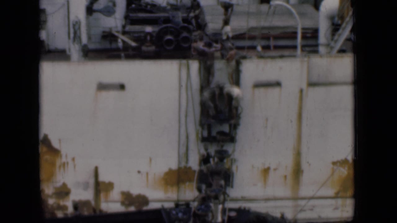1946 Bombay shipyard footage showing workers near the side of a white vessel with rust marks, pipes, and machinery overhead.