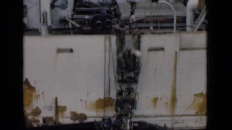 1946 Bombay shipyard footage showing workers near the side of a white vessel with rust marks, pipes, and machinery overhead.