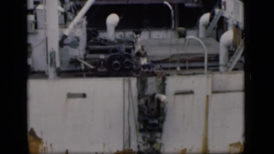 1946 Bombay footage showing people climbing or standing by a ladder against a large white ship with visible railings and equipment.