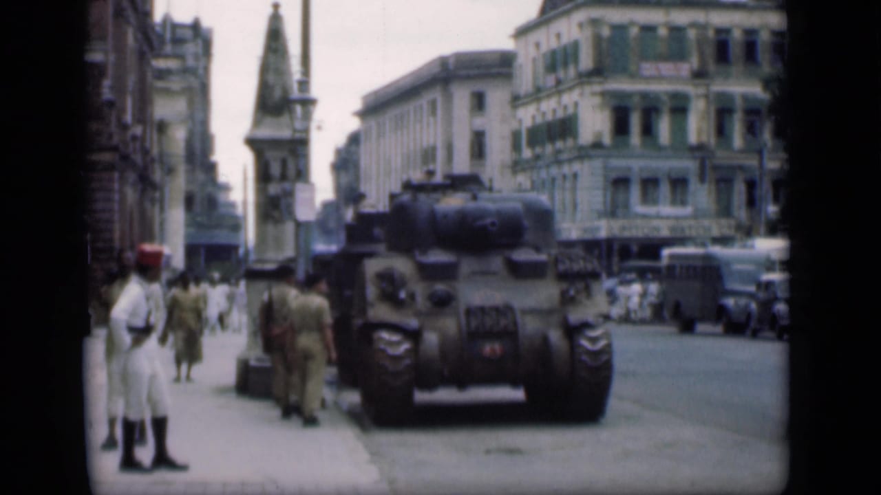 Tank parked beside a Bombay street with uniformed men and pedestrians nearby.