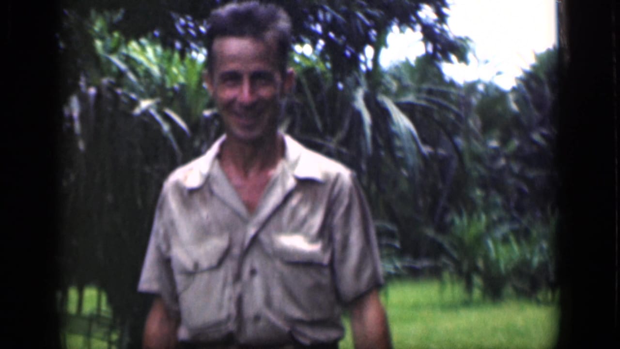 Smiling adult man approaching the camera in a tropical garden.