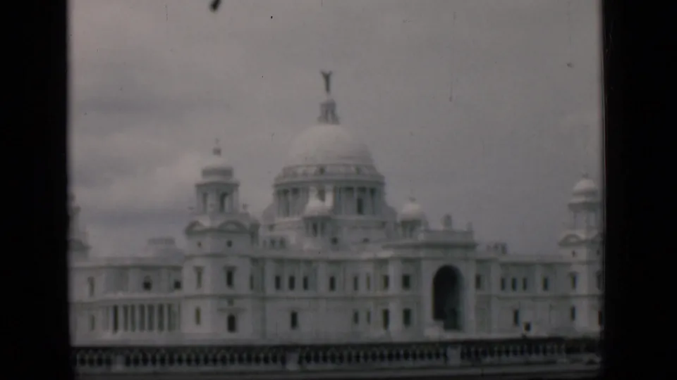 Muted-color 8mm frame of the supplied Victoria Memorial Hall identification, showing the domed facade and foreground railing.