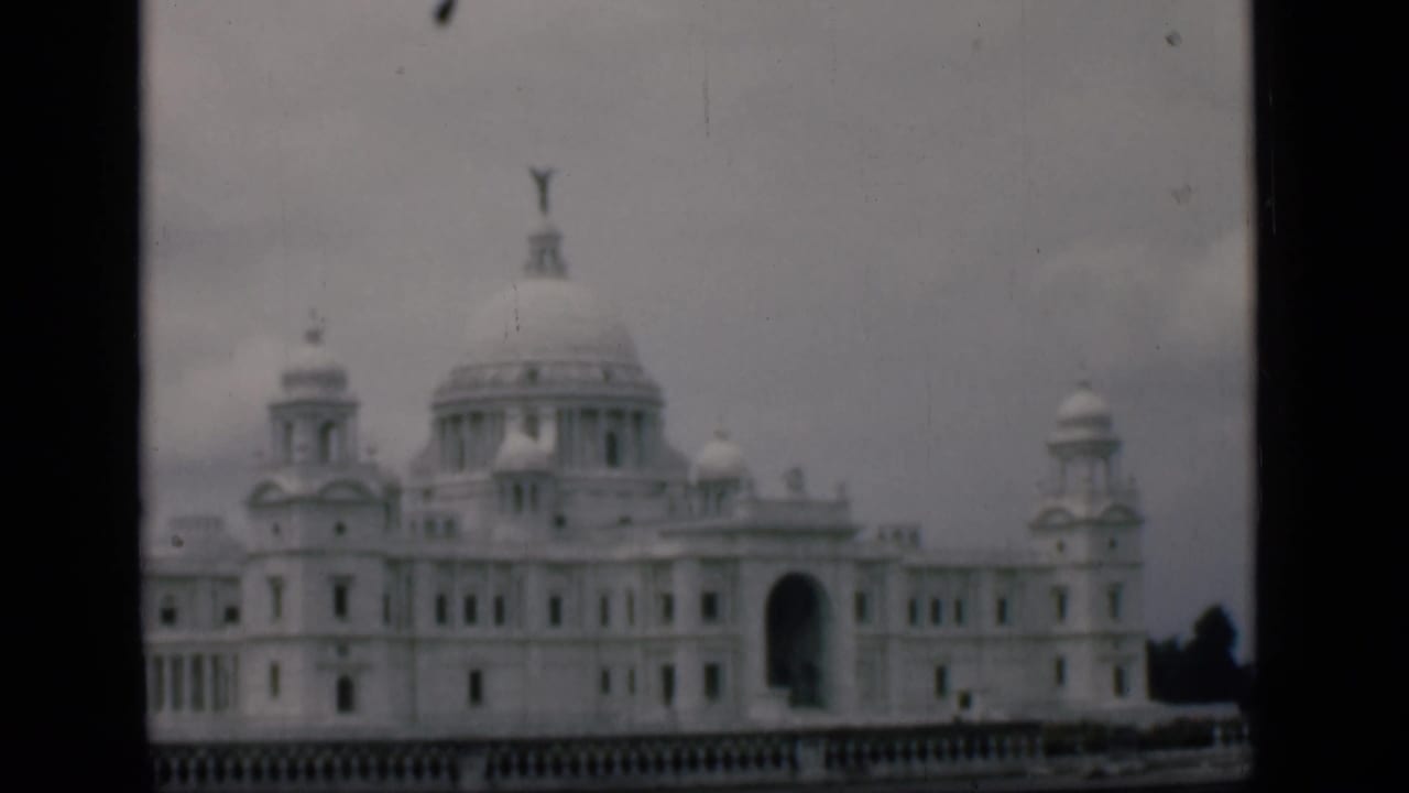 White landmark facade with central dome and dark arched doorway.