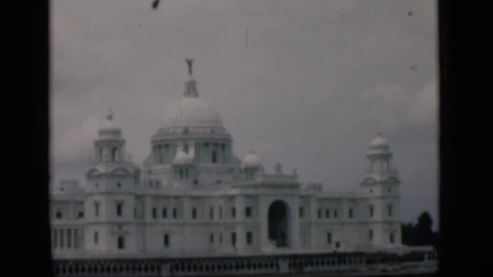 The 1946 Bombay home-movie frame holds on the white domed building, with small turrets and a dark central arch visible.