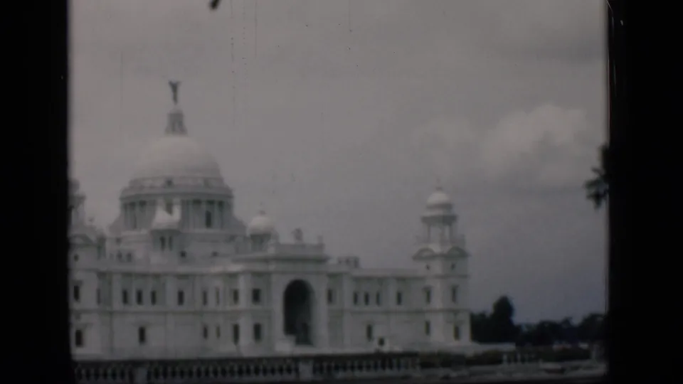 The final 1946 Bombay frame shows the domed white landmark with a dark arch, low railing and tree silhouettes near the right edge.