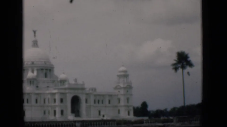 1946 Bombay-labeled home-movie frame of a domed colonial-style exterior partly divided by a dark foreground edge.