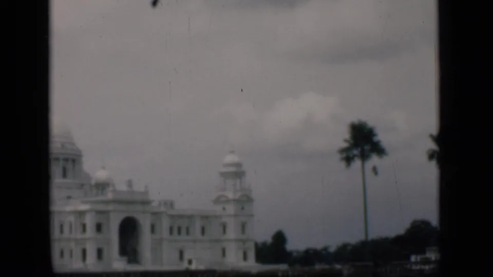 1946 Bombay-labeled 8mm view with the building shifted left, showing its arched entrance, dome, and palm trees.
