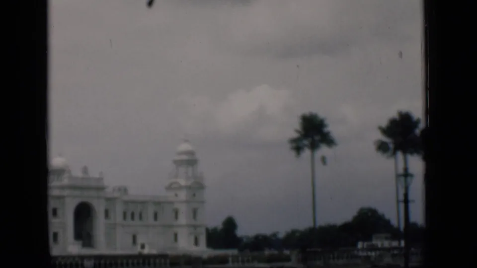 Late frame from the 1946 Bombay-labeled clip, with a cropped domed building, arched opening, palms, and overcast sky.