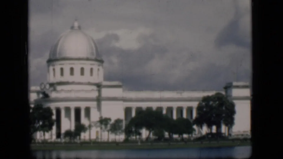 End frame from 1946 Bombay showing the domed white building softened by 8mm focus, with trees and water in the foreground.