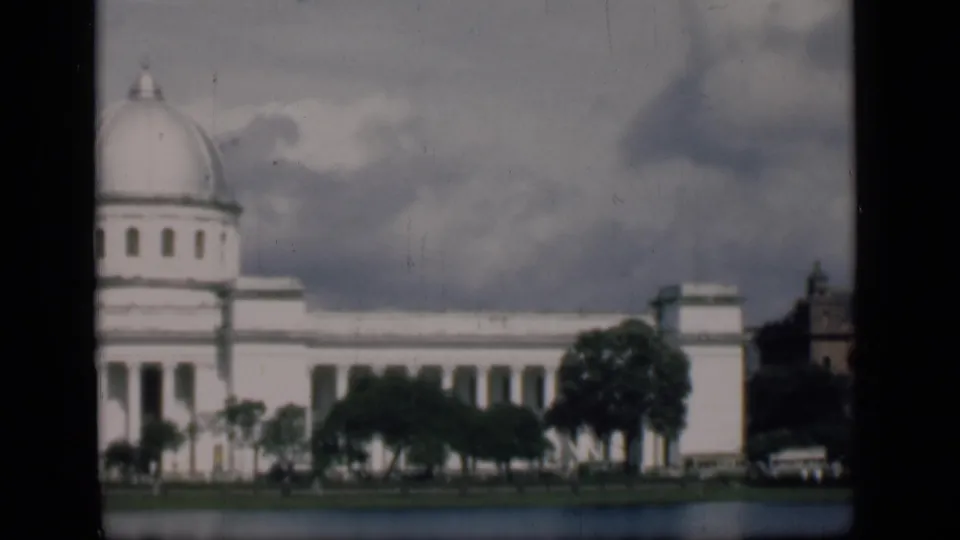 1946 Bombay frame showing the domed white civic facade, roadside trees, and a small automobile near the right edge.