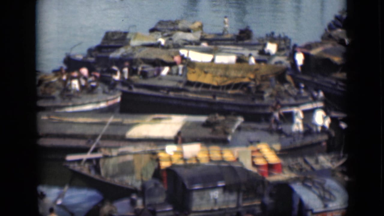 Crowded wooden boats and barges moored beside a dock with cargo and people visible on deck.
