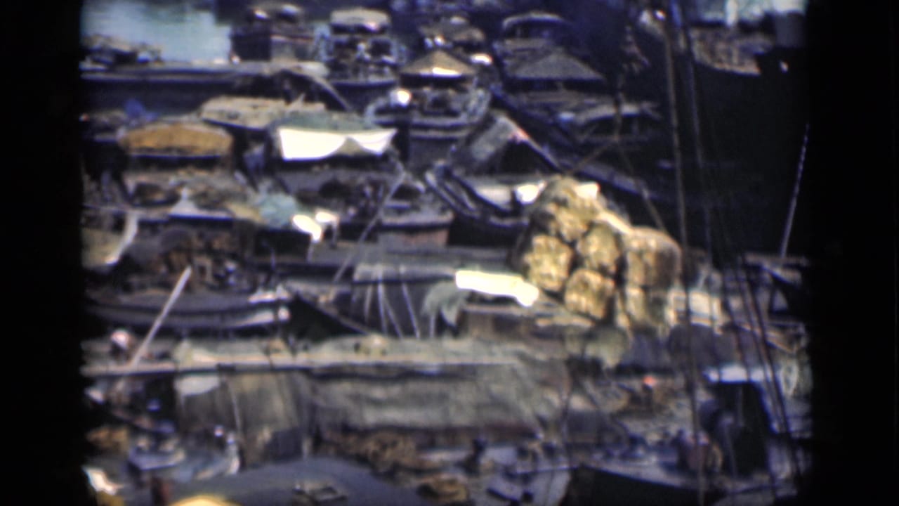 Similar overhead view of boats, sheds, tarped goods, and rigging.