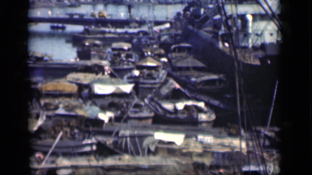 Crowded harbor with small boats moored beside larger vessels and dock structures.