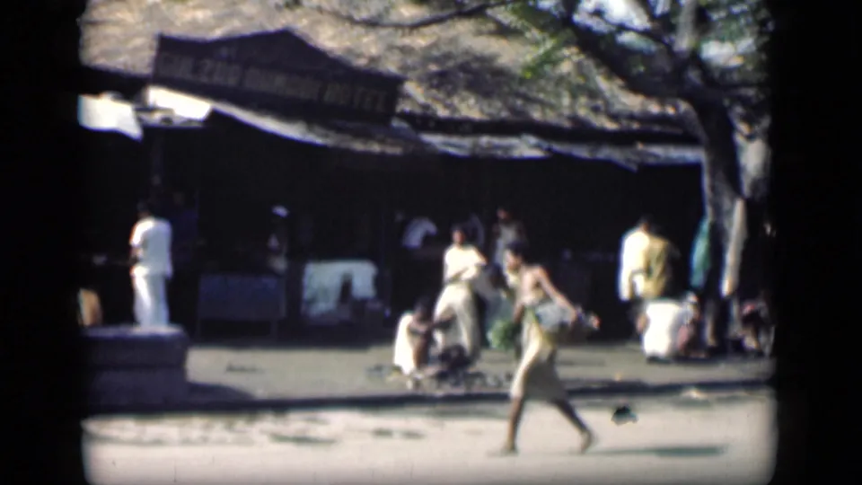 Bombay, 1946 street footage showing several pedestrians near a shaded hotel or market frontage with signage overhead.