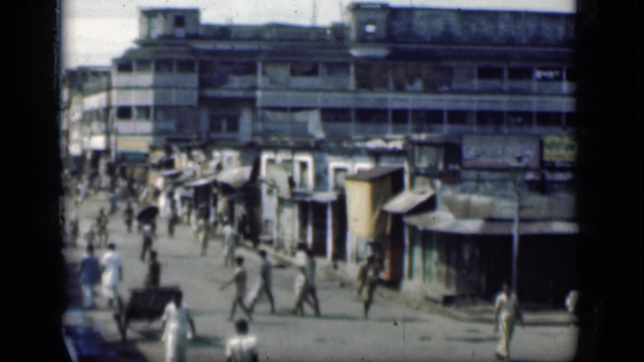 Pedestrians walk past small shops below a weathered multi-story building.