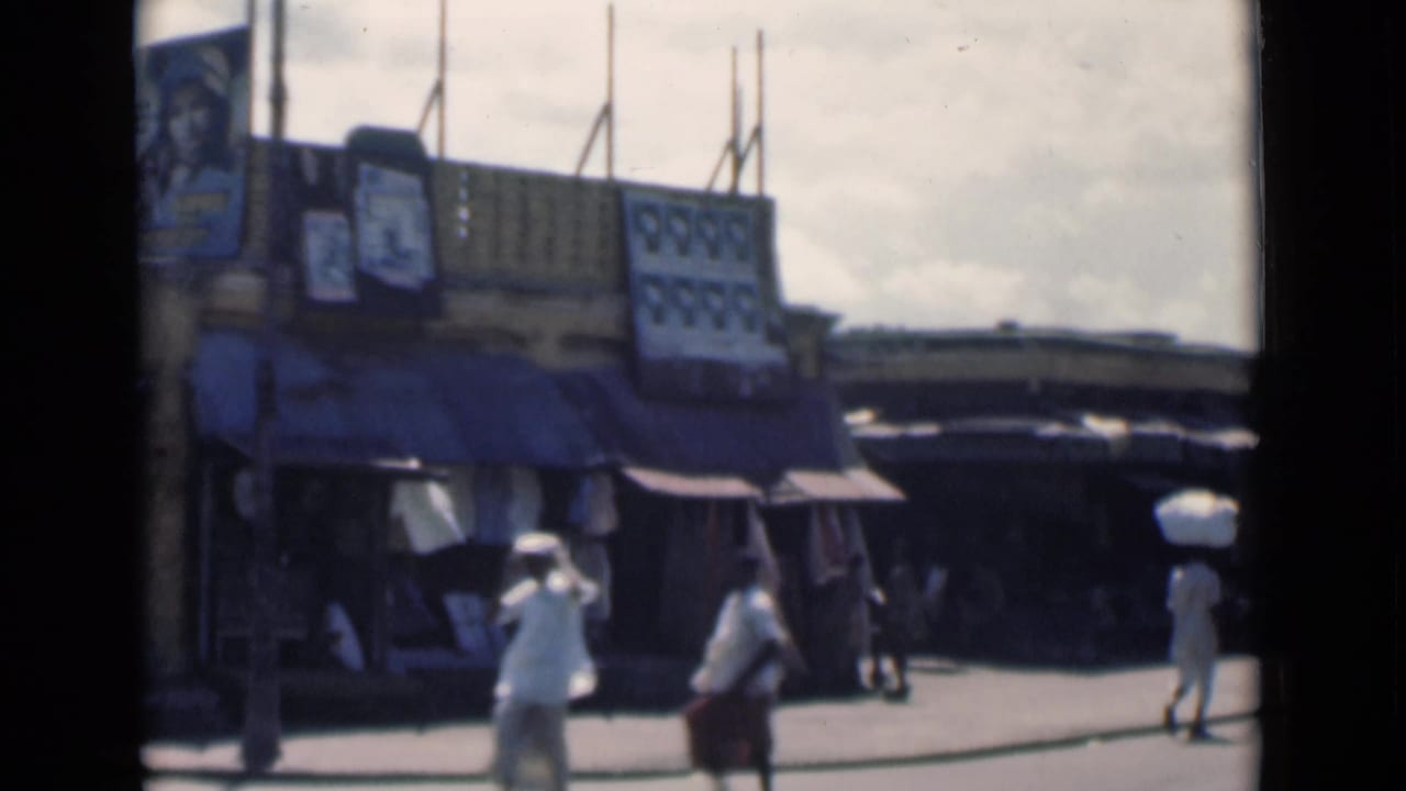 1946 Calcutta street view with shop awnings, pedestrians and a man in white balancing a large bundle on his head.