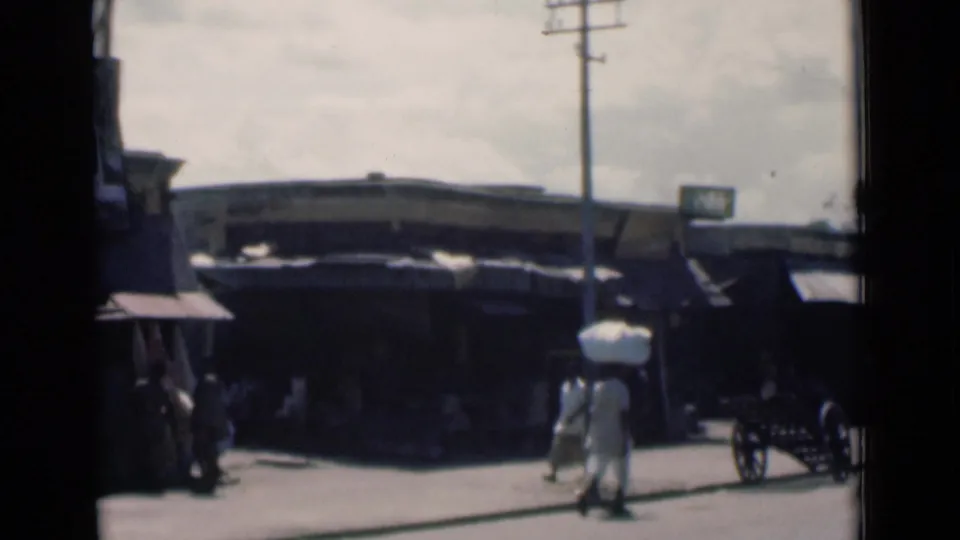1946 Calcutta street footage showing a bundle carrier near a telephone pole, shaded shops and a handcart.