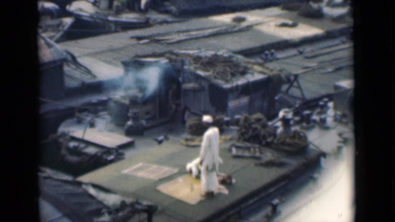 High-angle 1946 Calcutta ship-deck view with a man in white clothing on a prayer mat amid ropes, equipment, and smoke.