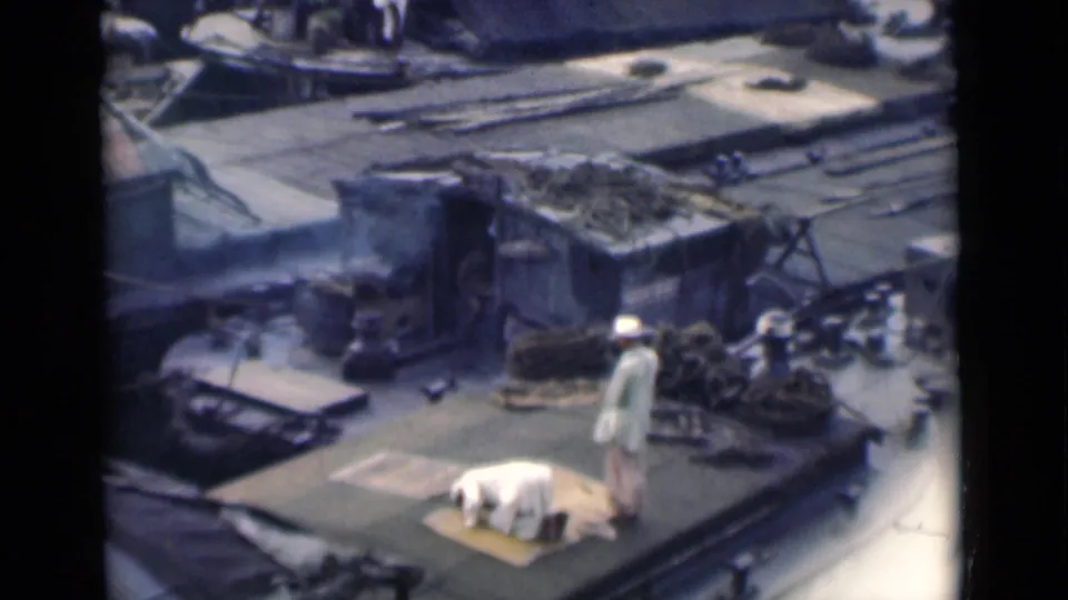 The 1946 Calcutta clip ends with the prayer posture visible beside rooftop ropes, smoke and worn structures.