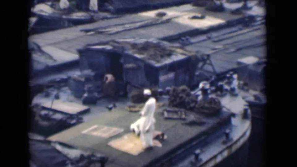 The Calcutta boat scene shows a man in white seated or kneeling on a prayer rug, with another person partly visible near the deck structure.