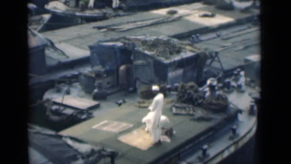 The prayer sequence continues in a soft 8mm frame showing a man kneeling on a rug on a ship deck in Calcutta, India.