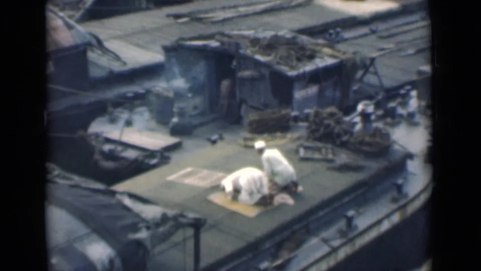 The Calcutta boat deck scene shows one man kneeling in prayer on a mat as another man in white stands nearby among ropes and cargo.